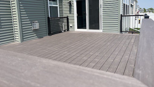 View of a new composite deck from the drink rail looking in toward the house & sliding door.